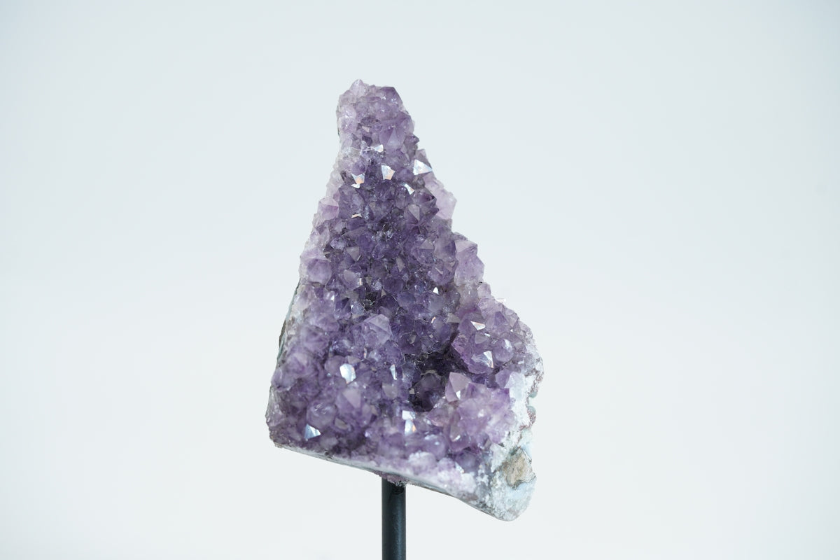 A cluster of purple amethyst crystals on a stand.