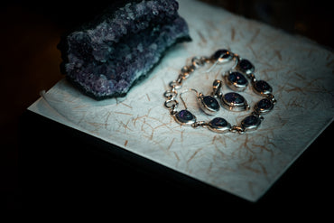 Amethyst jewelry and raw crystal on textured paper